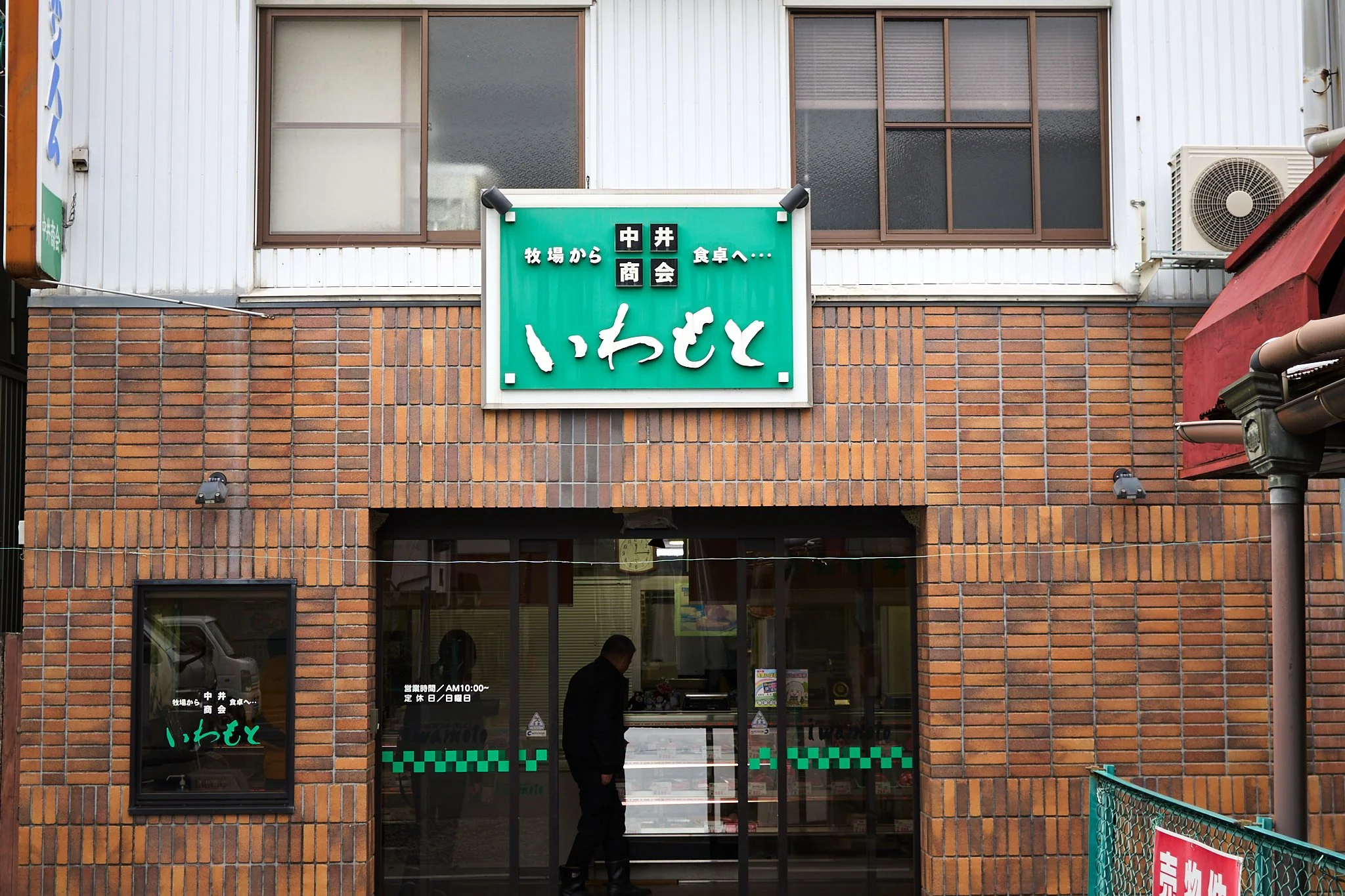 店舗の入口と看板、窓に貼られた営業情報