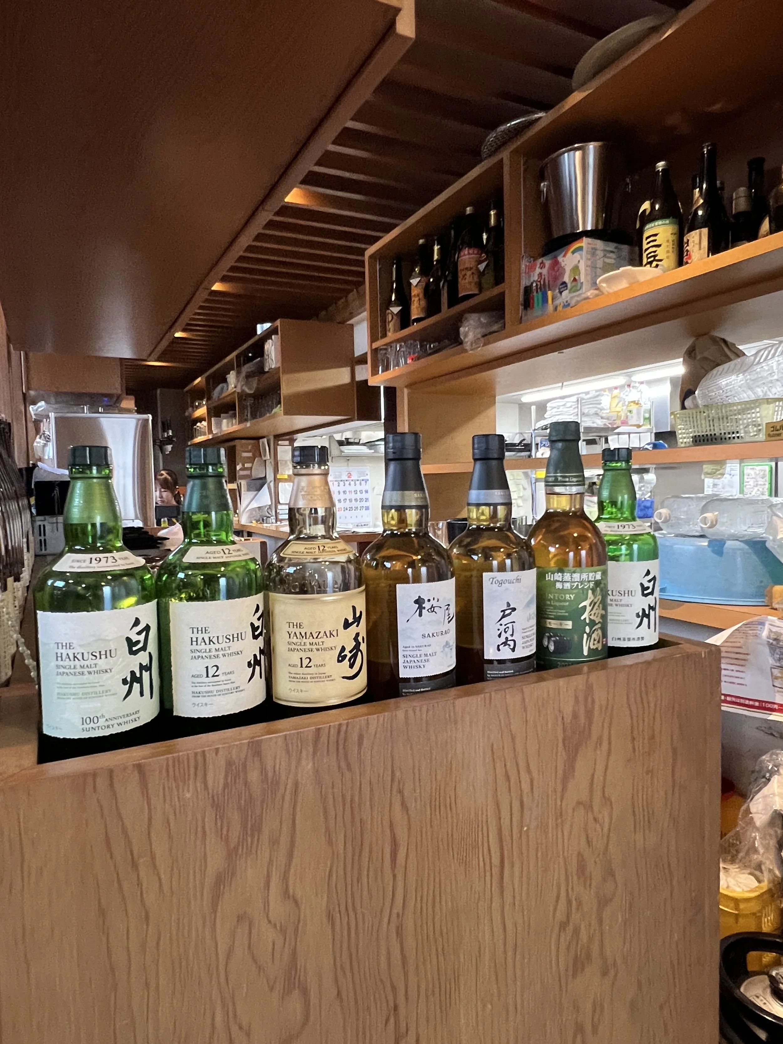  barのカウンターに並ぶ複数の日本のウイスキーのボトル