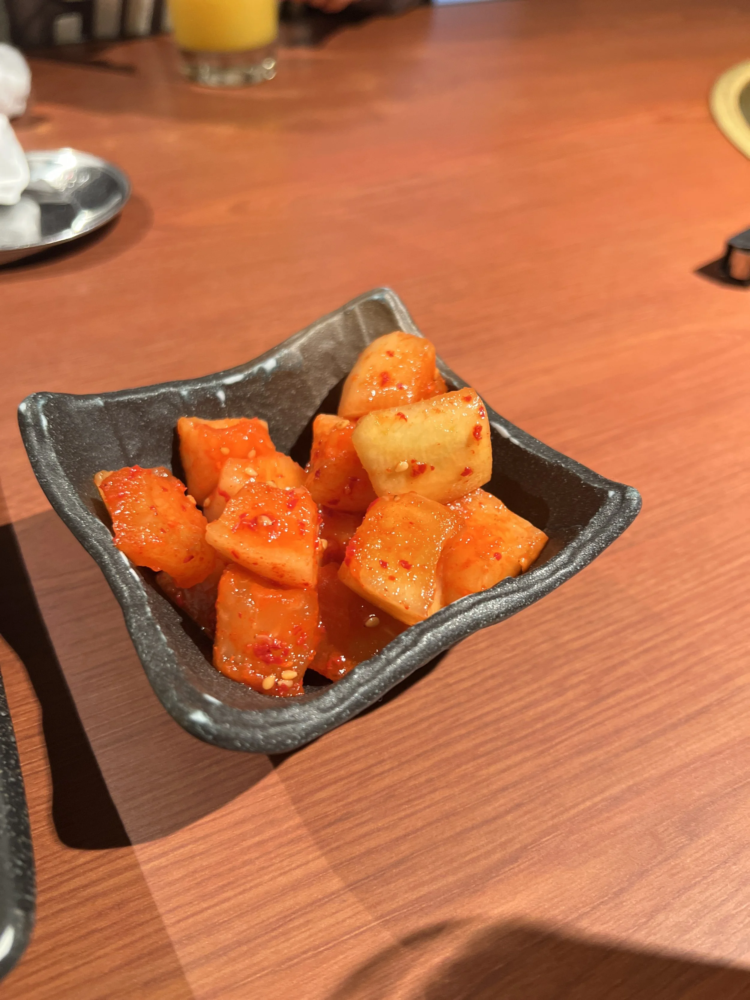 小さな黒い皿に盛られたキムチの大根ときゅうりのピクルス