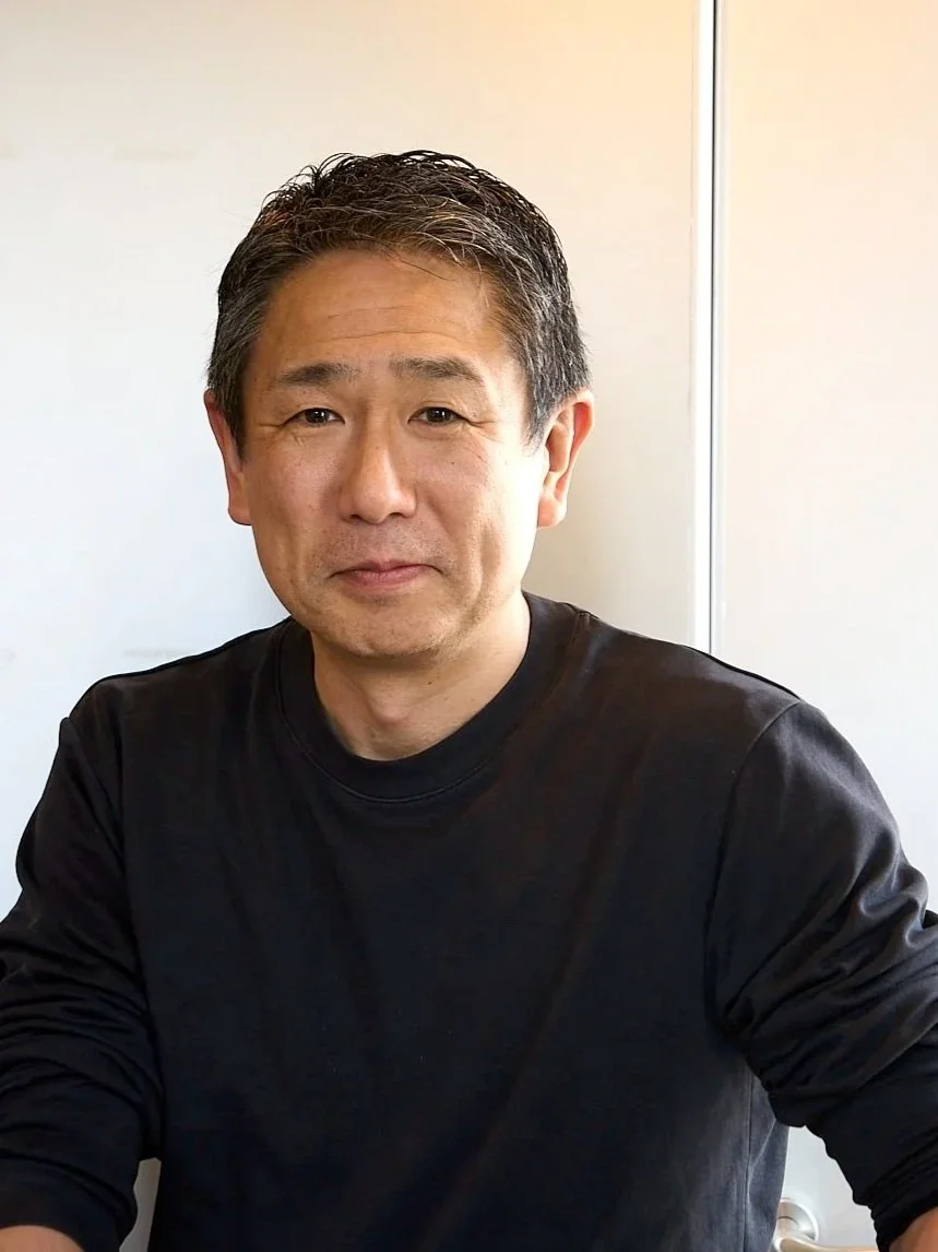 黒のシャツを着た中年の男性が座っている