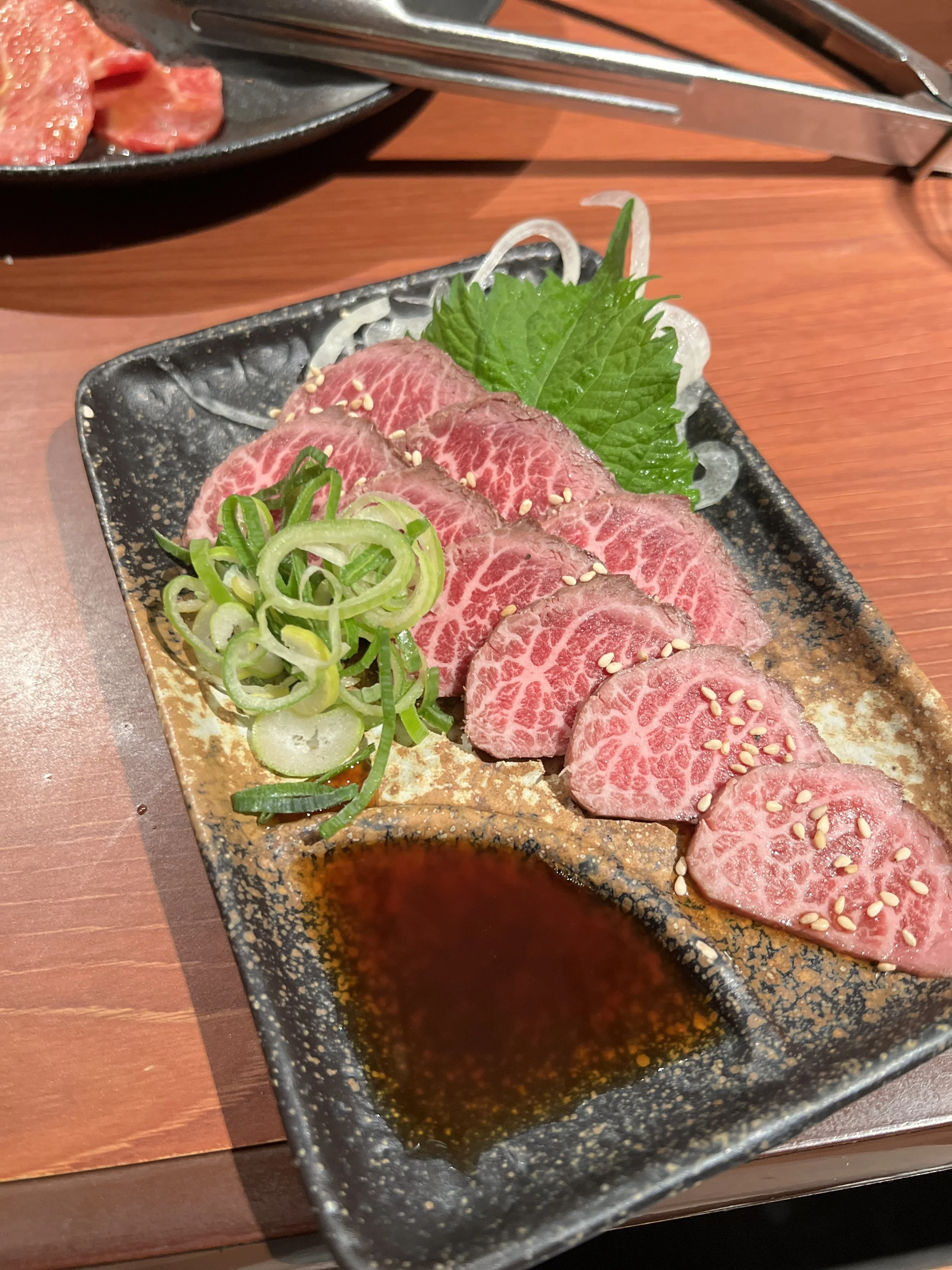 霜降りの牛肉刺身と刻みネギ、香草と醤油