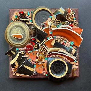 Collage of broken ceramic and glass pieces, some resembling parts of cameras, arranged on a square wooden base.