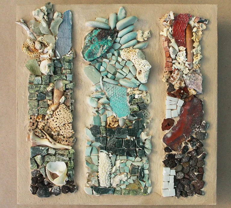 A mosaic art piece made with various small stones, shells, and ceramic fragments arranged in three vertical sections.