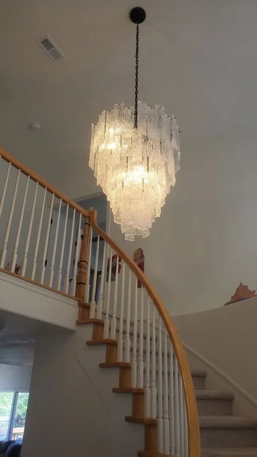 Crystal chandelier installation in Thornton — Installation of a crystal chandelier in a Thornton home. The finished light fixture hangs above the curved staircase.