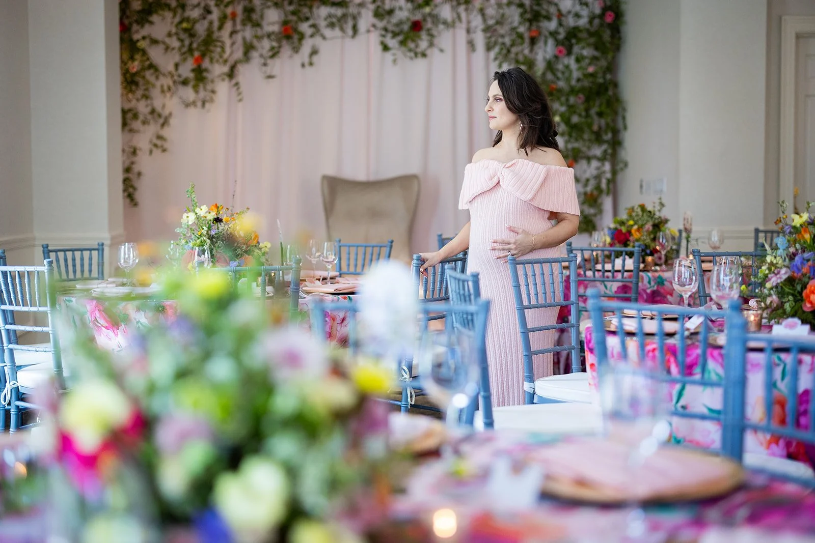 Expectant mother in pink off-shoulder dress standing in fully decorated ballroom at Morrison House Old Town Alexandria