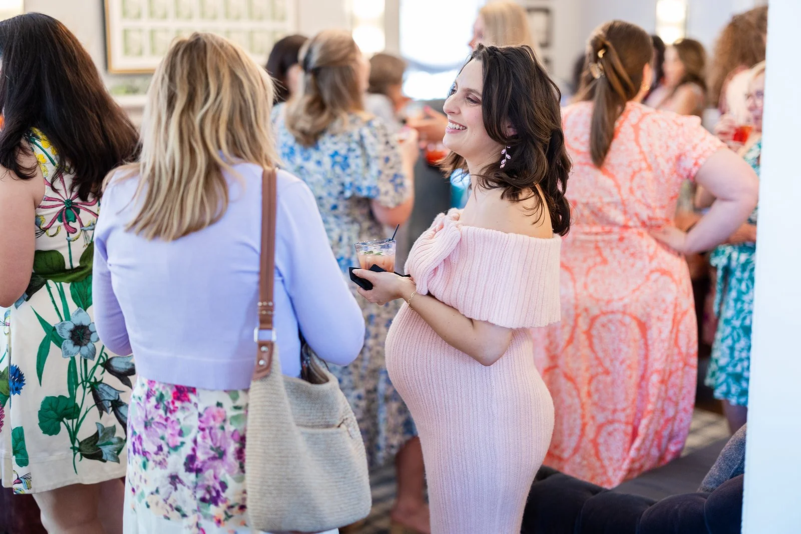 Candid moment of expectant mother laughing with friends during event reception at Morrison House Alexandria