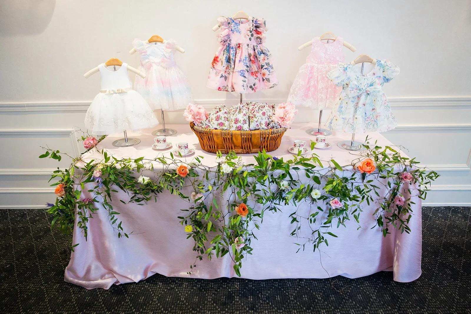 Decorative display table with infant dresses and cascading floral garland at Morrison House Alexandria event venue