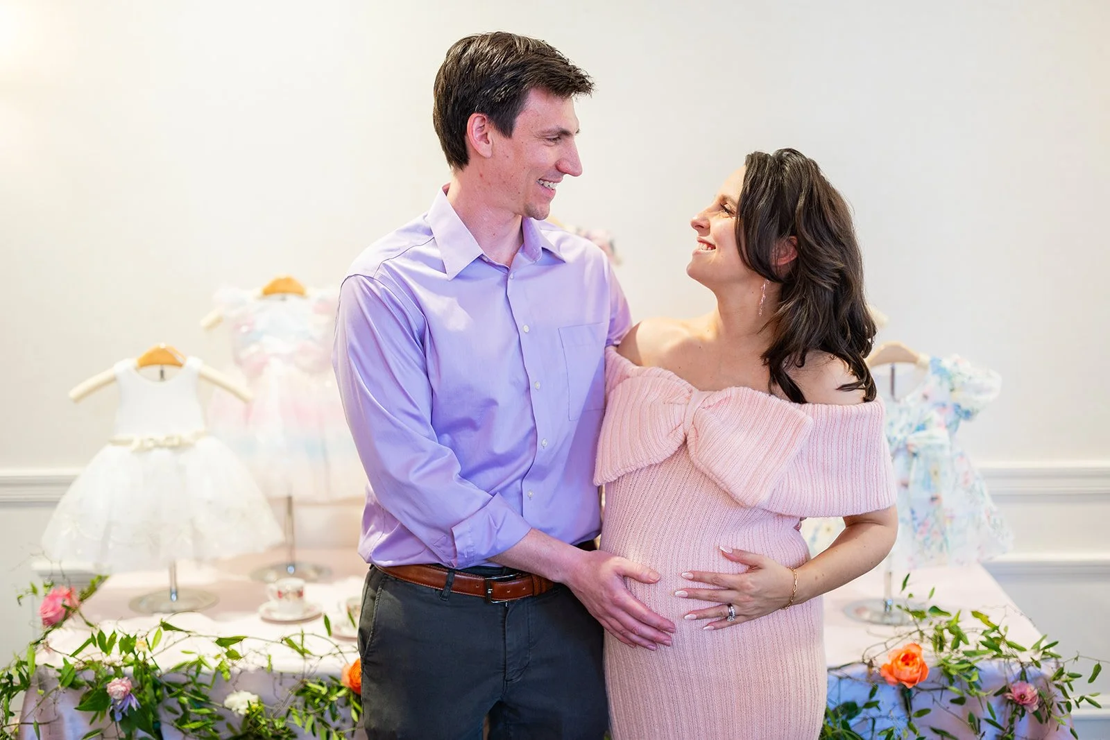 Couple portrait in front of decorative infant dress display at Morrison House Alexandria celebration event