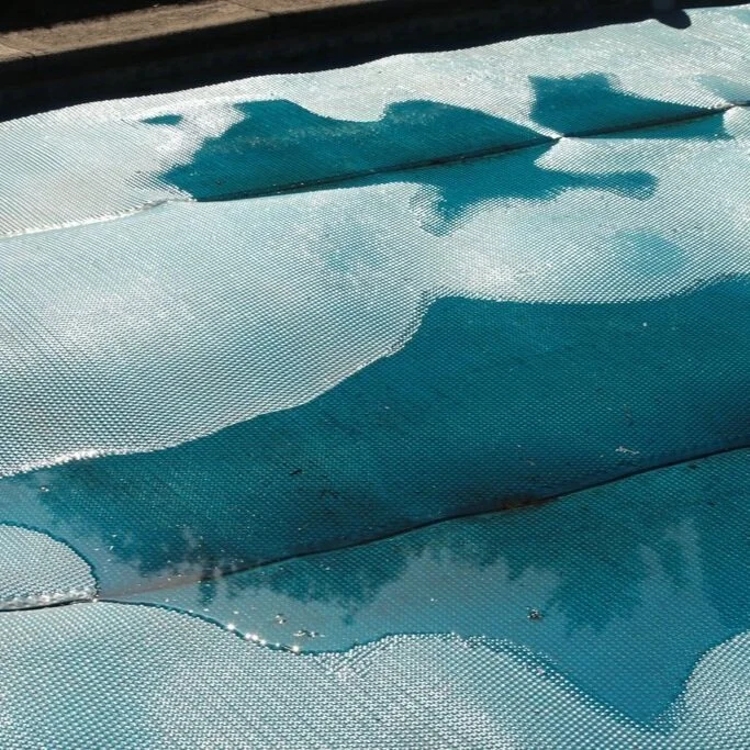 Close-up of a swimming pool cover with water on the surface.