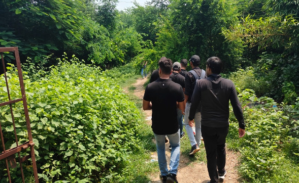 Group of people walking on a dirt path through lush green foliage and trees.
