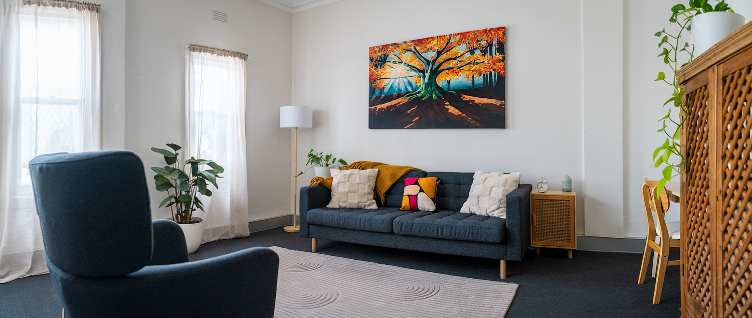 Consulting room with comfortable seating, indoor plants and autumn landscape artwork.