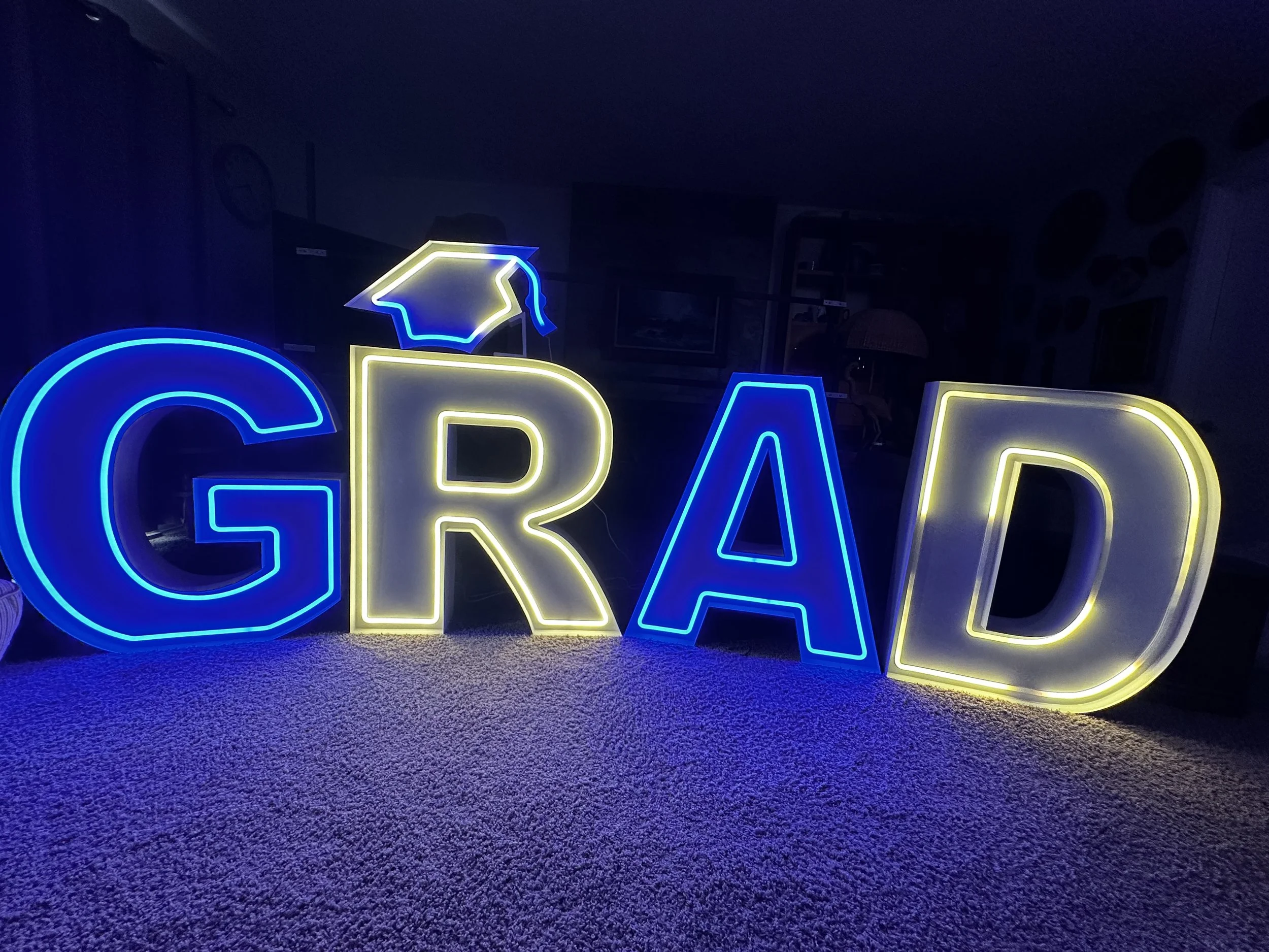 Colorful neon sign spelling 'GRAD' with a graduation cap on the letter 'G'.