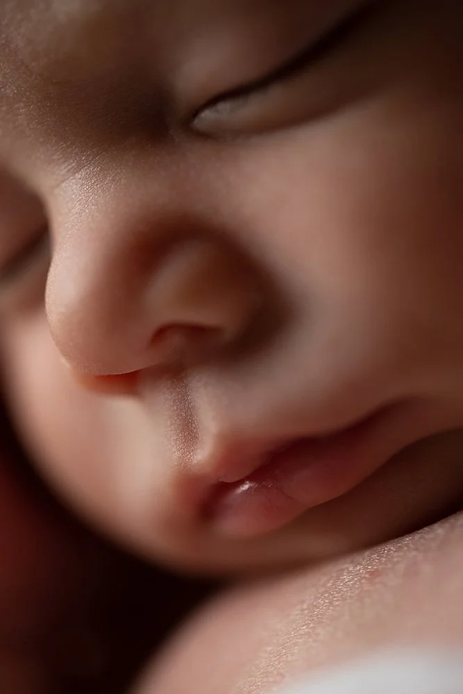 Close-up of a sleeping baby's face, showing closed eyes, nose, and mouth.