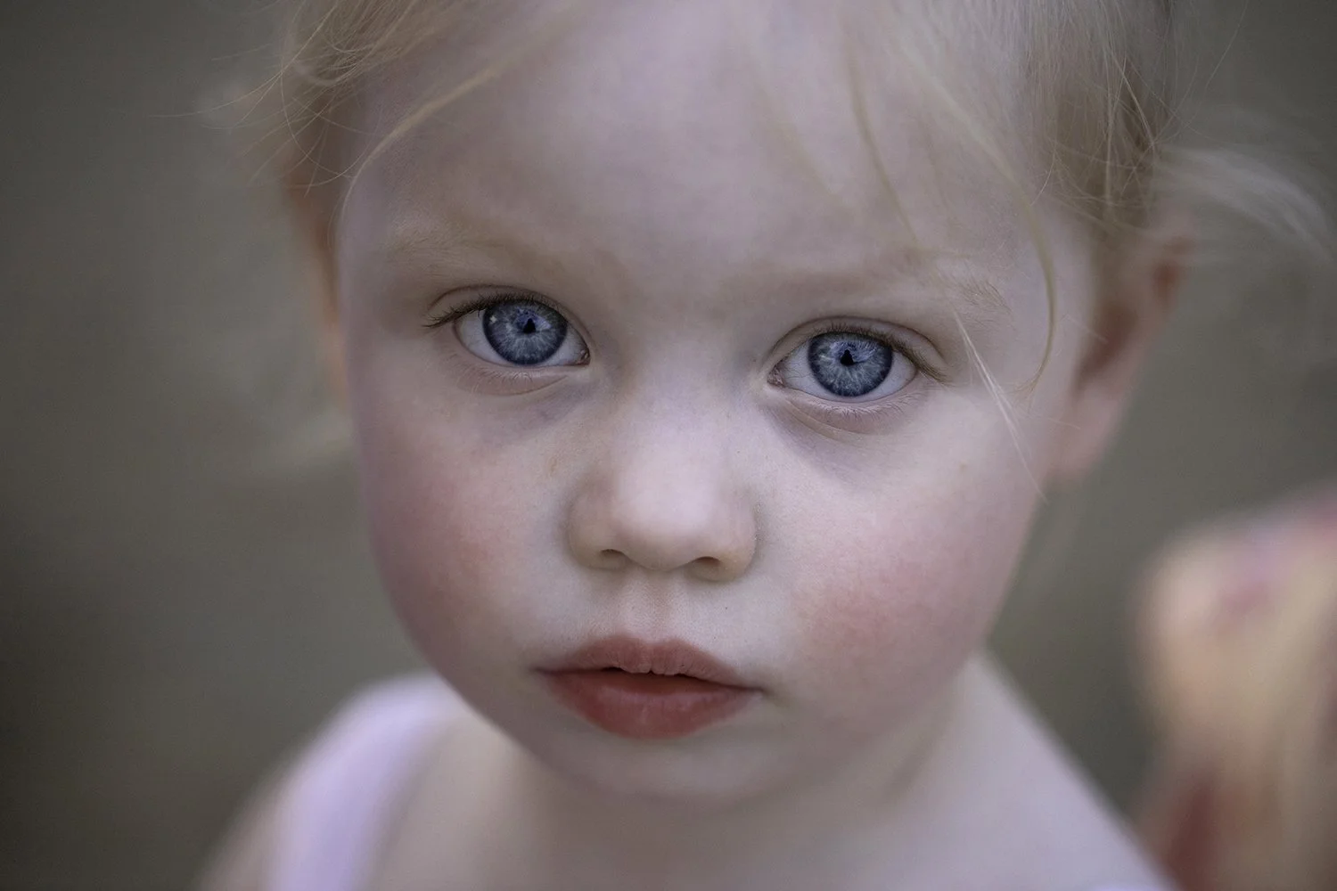 Close-up of a young child with blue eyes, light skin, and reddish-blonde hair.