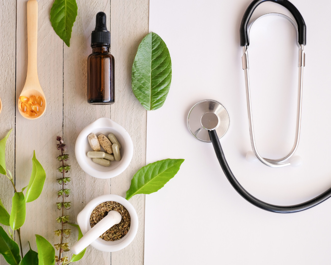 Arrangement of natural remedies and medical tools, including herbal leaves, capsules, pills, dried herbs, medicine dropper, and a stethoscope on a white surface.