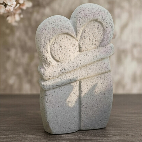 A perfect gift sculpture of two people hugging, sharing a heart-shaped space handcrafted from natural textured concrete.