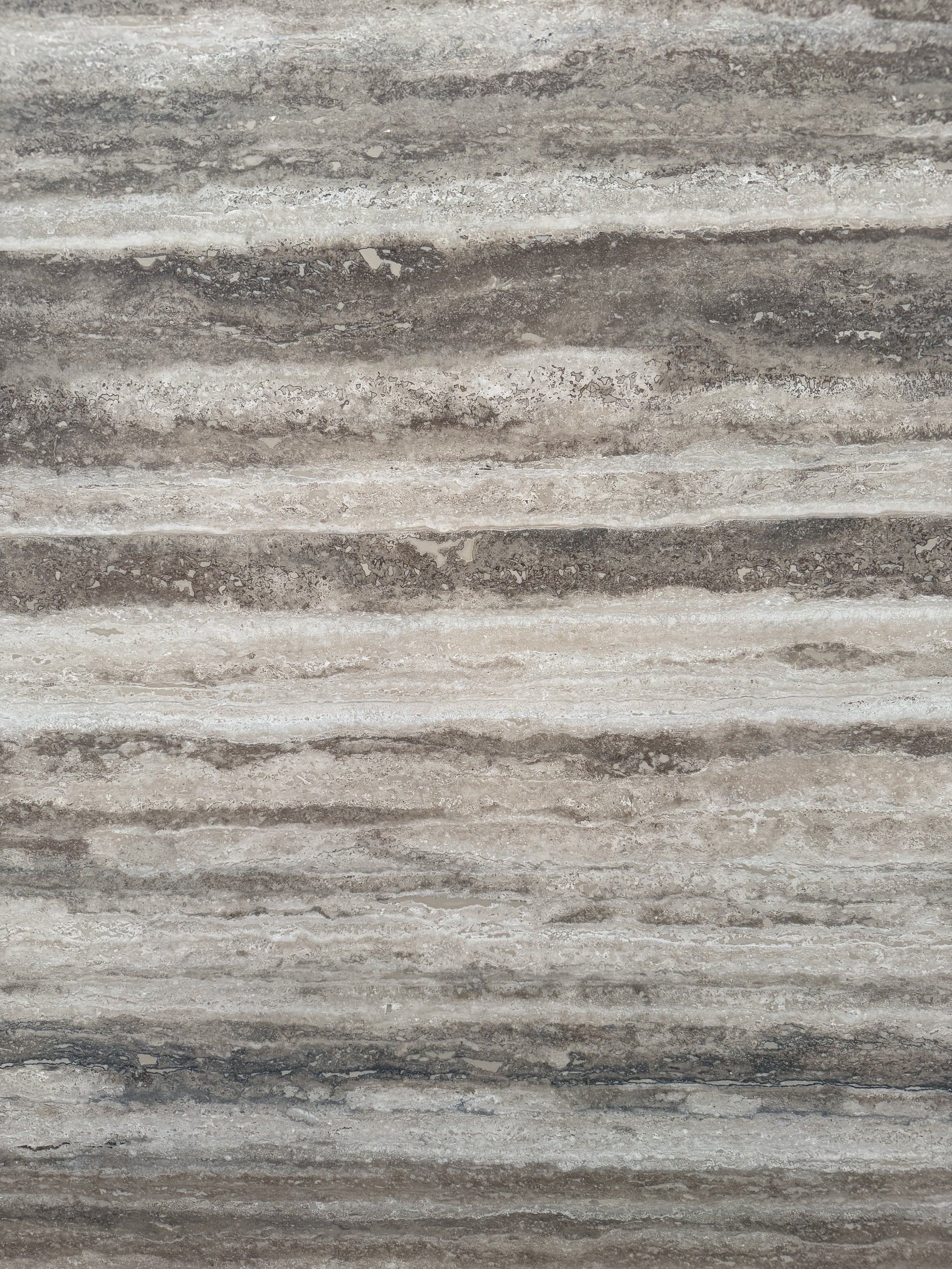 Close-up of natural stone with layered grey, taupe and cream veining, illustrating the use of texture and natural materials in interior design.