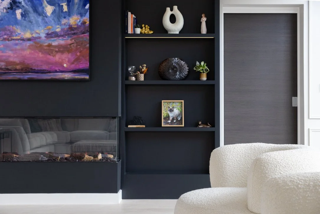 Modern dark built-in shelving styled minimally with sculptural decor, books and small plants.