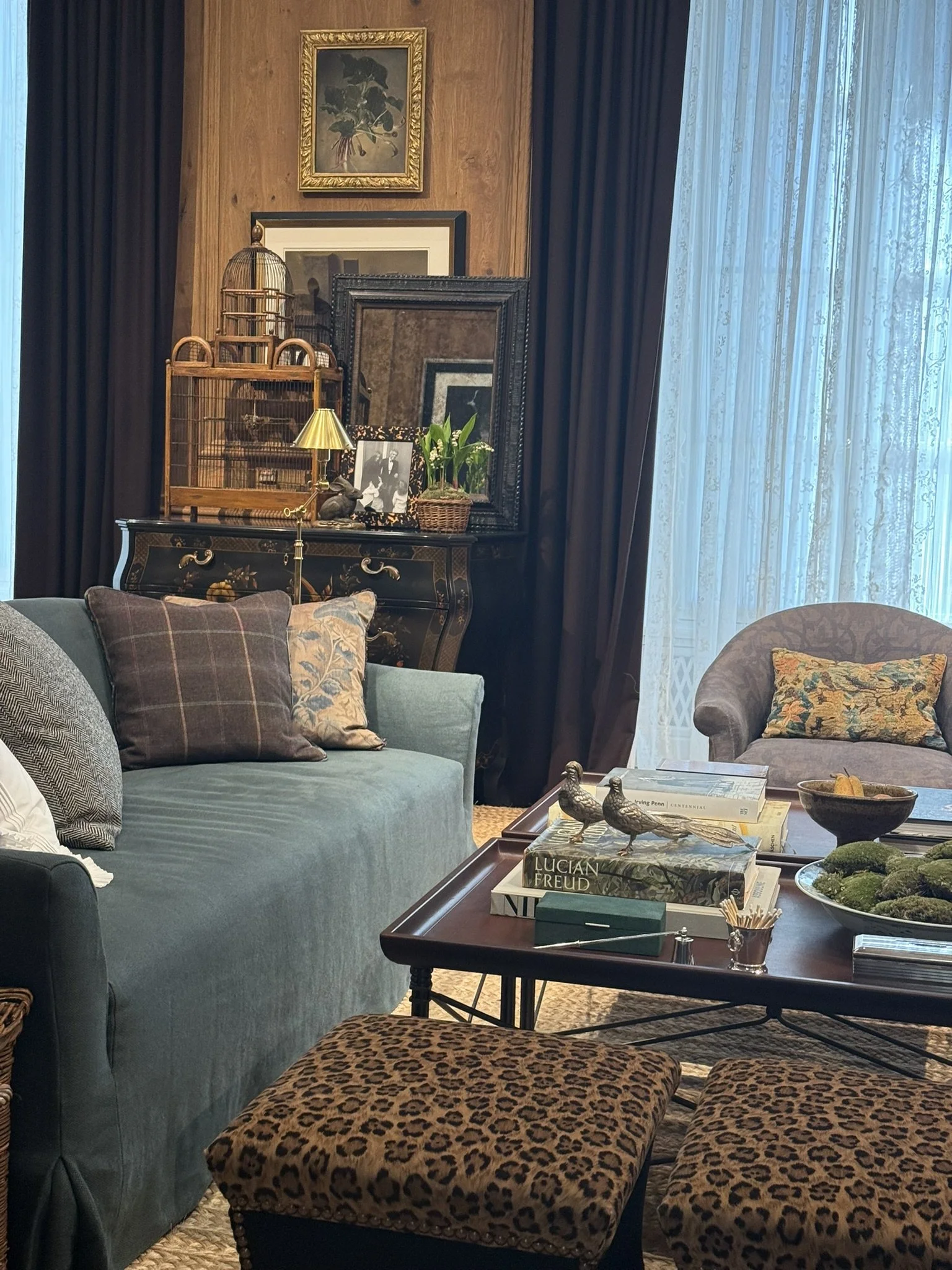 Traditional living room with layered coffee table styling featuring books, decorative objects and moss bowl arrangement. From the Ralph Laurent Home showroom in Milan.