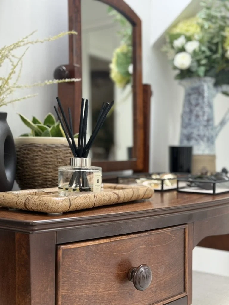 Wooden console table styled with tray, diffuser, vases and layered decorative accessories.