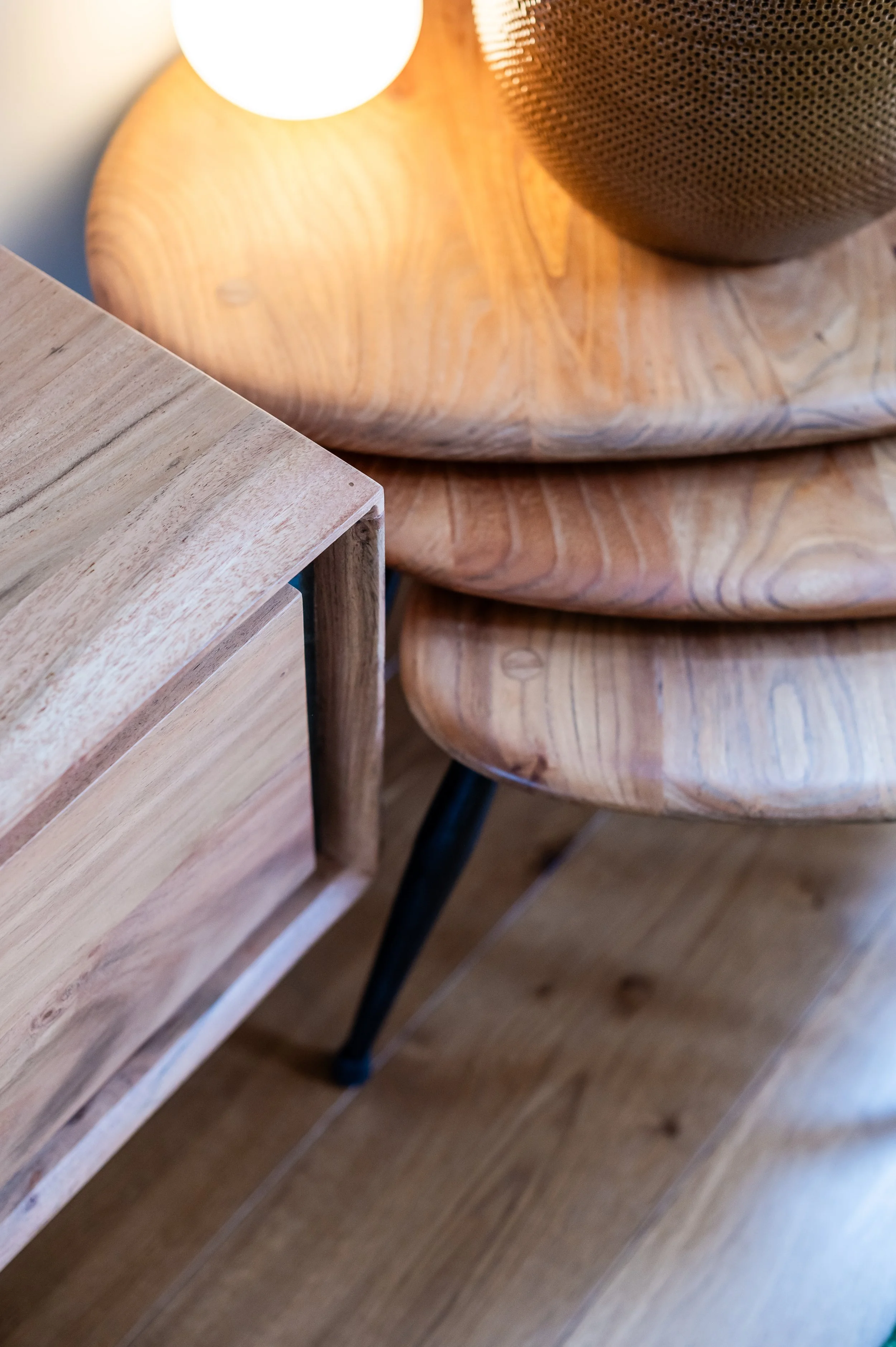 Close-up detail of warm natural wood furniture and layered organic textures, featuring sculptural timber surfaces, soft ambient lighting and modern organic styling with handcrafted character.