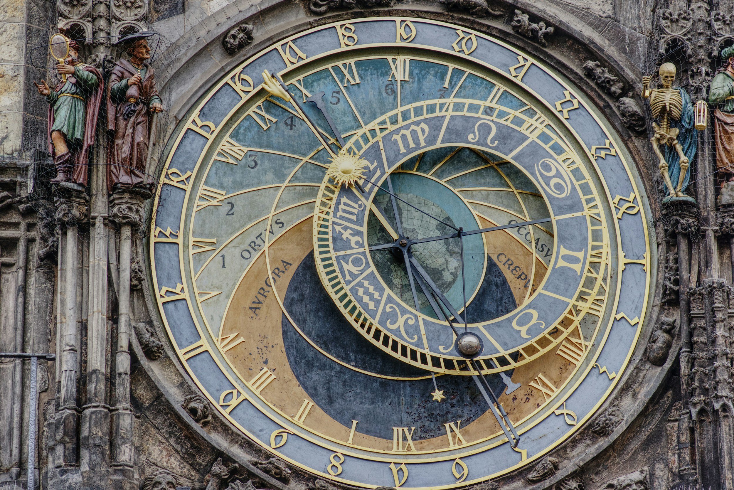 The Prague astronomical clock showing time, zodiac signs, and celestial information with ornate statues on the sides.
