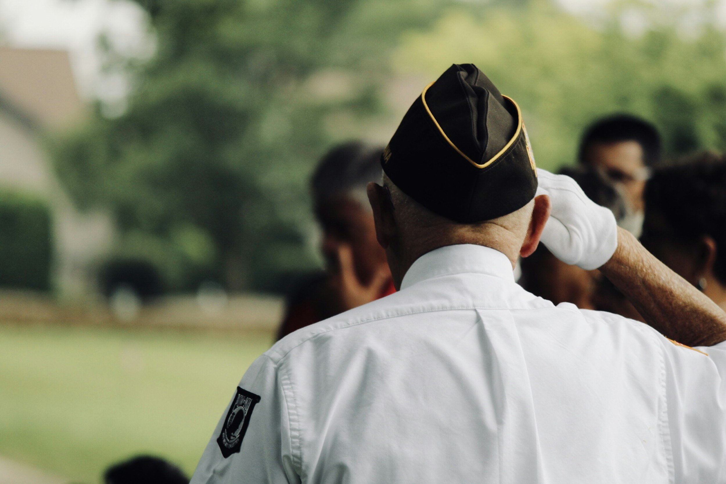 A police officer in uniform salutes during a ceremony, with other people in the background.