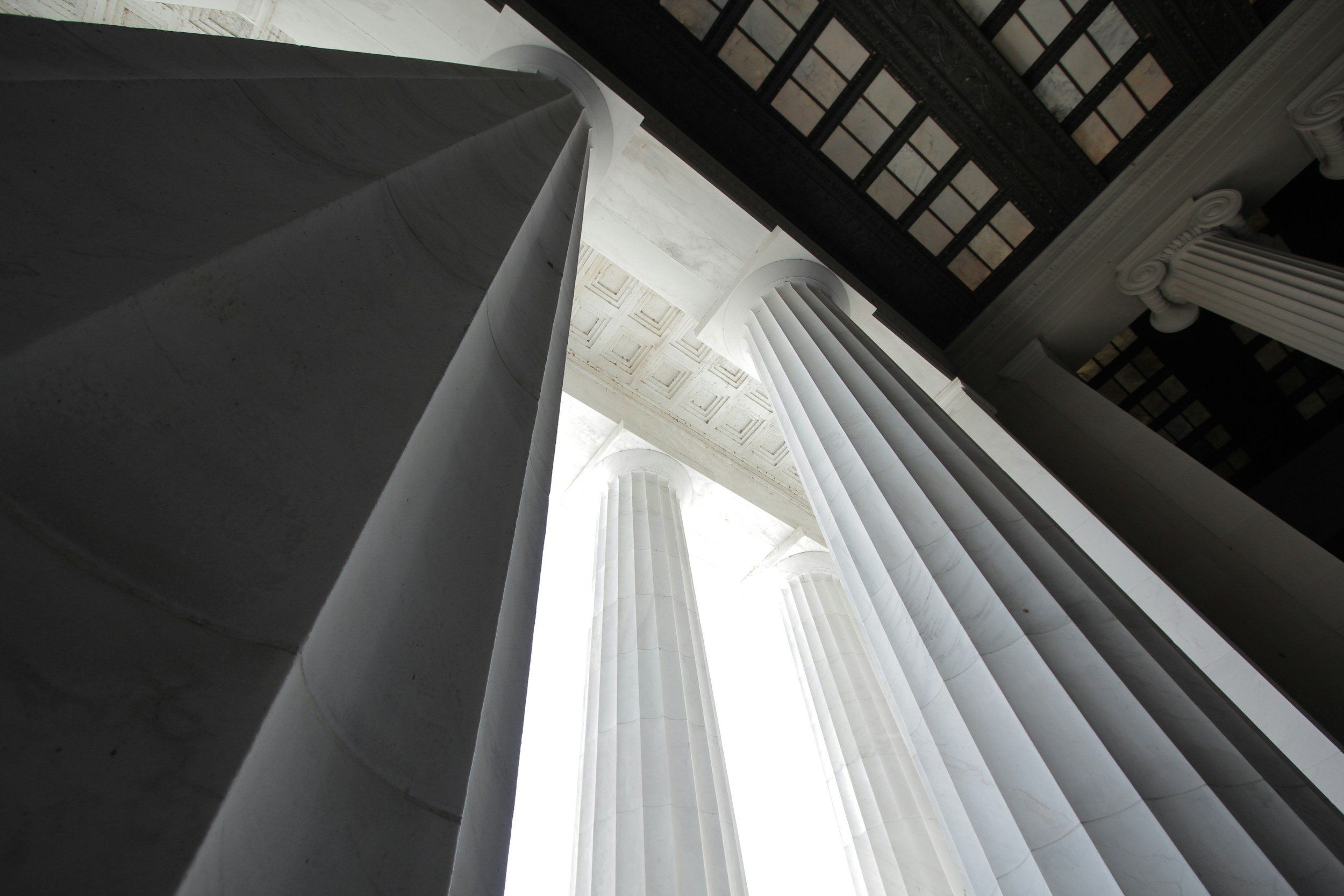 Low-angle photo of tall, white marble columns inside a classical building.