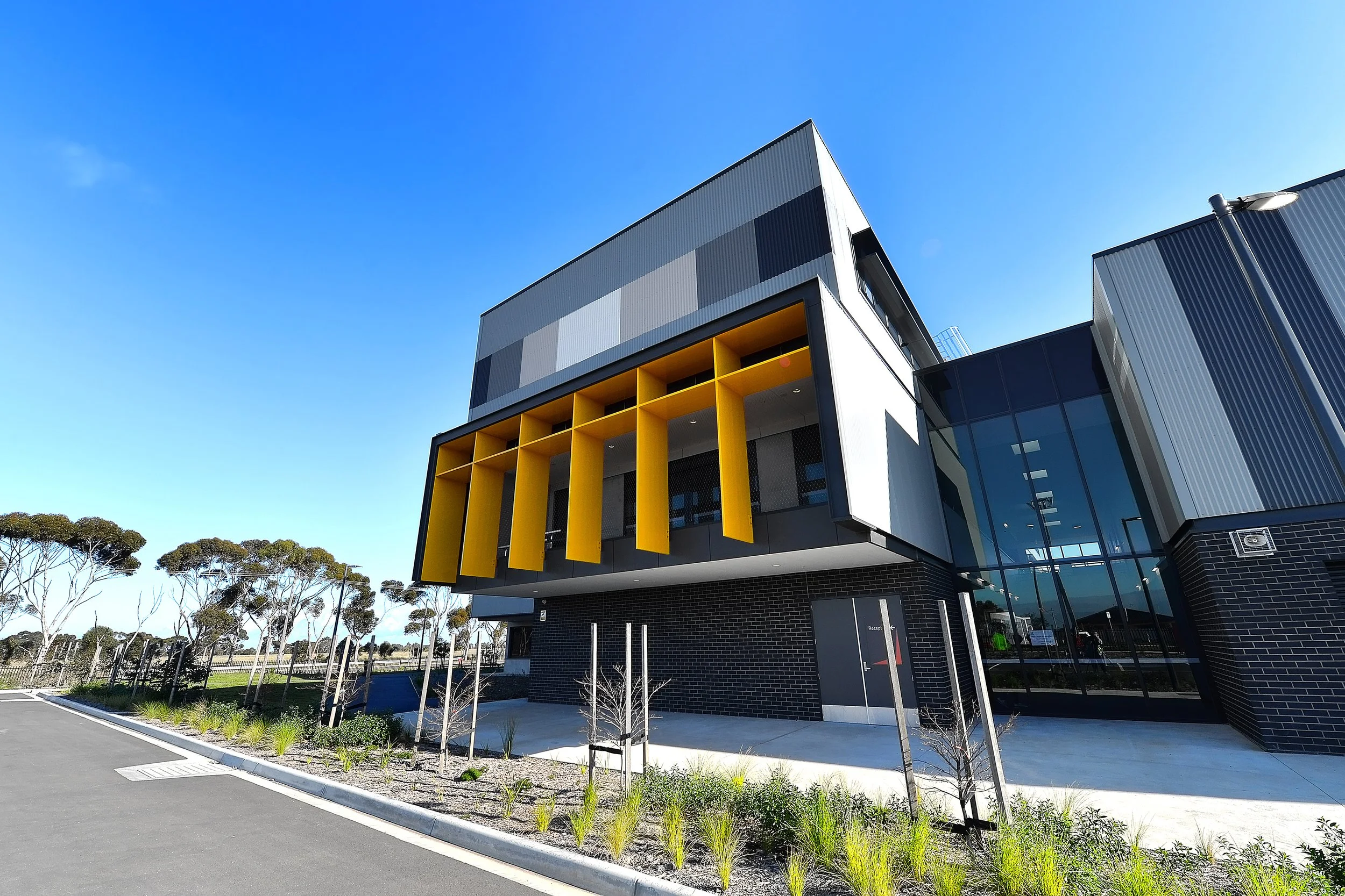 Modern building with black, gray, and yellow accents under a clear blue sky.