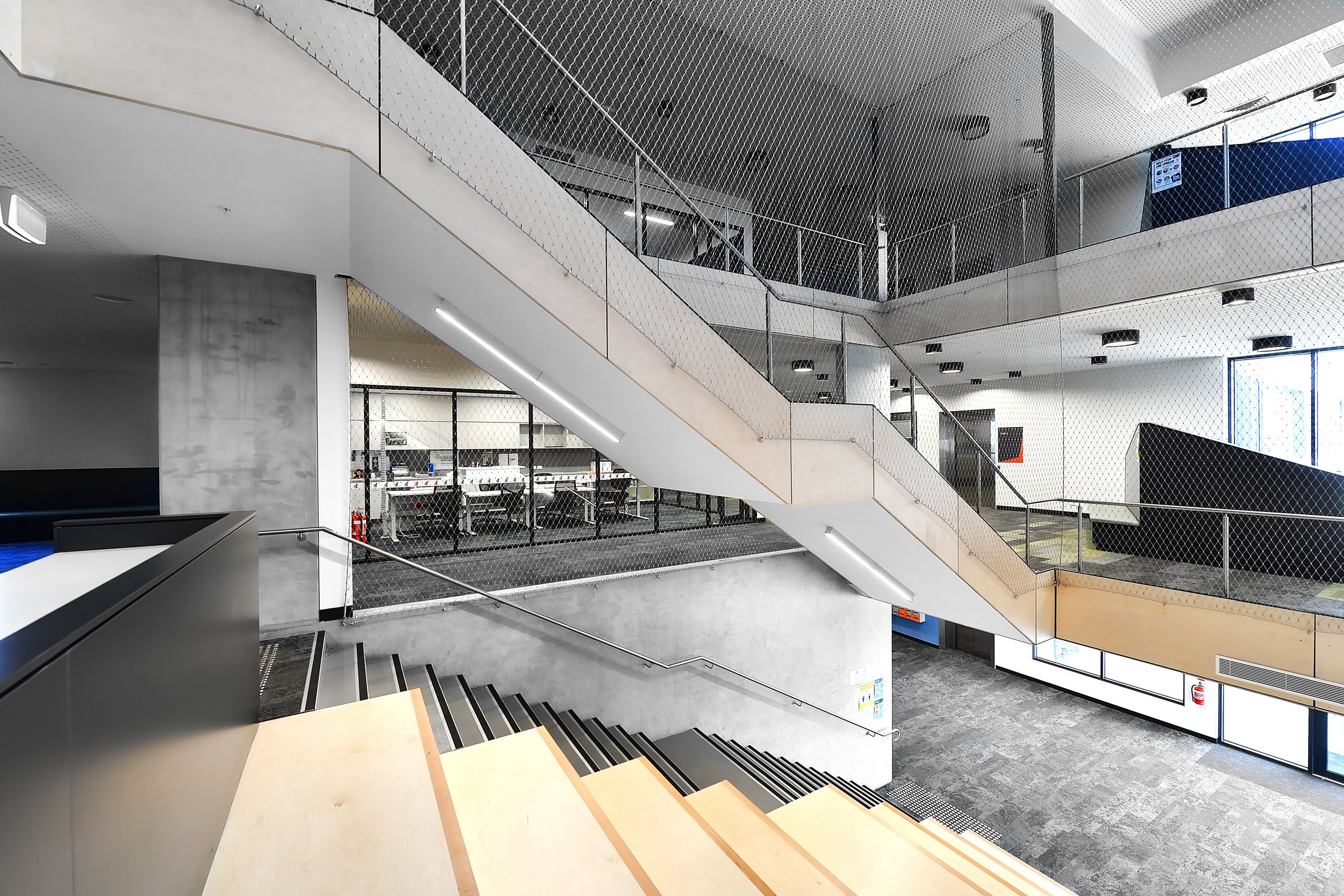 Interior view of a modern, multi-level office with staircases, glass partitions, and open workspaces.