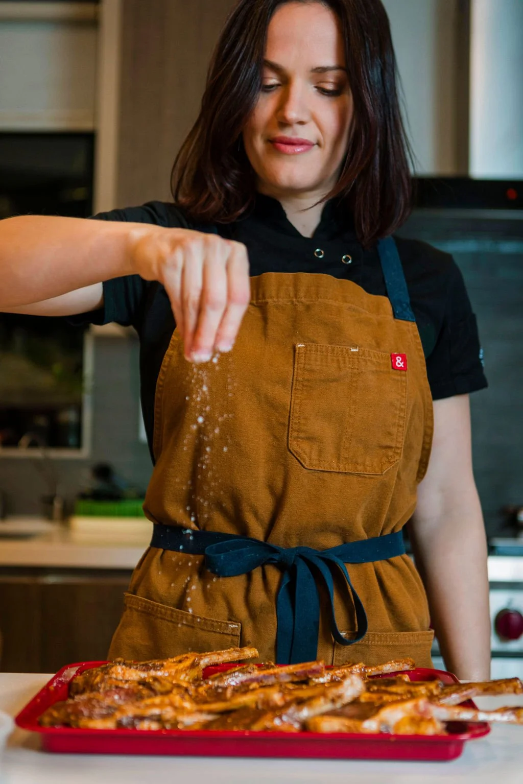 From above hands of unrecognizable woman rubbing aromatic spices into piece of raw meat over parchment paper