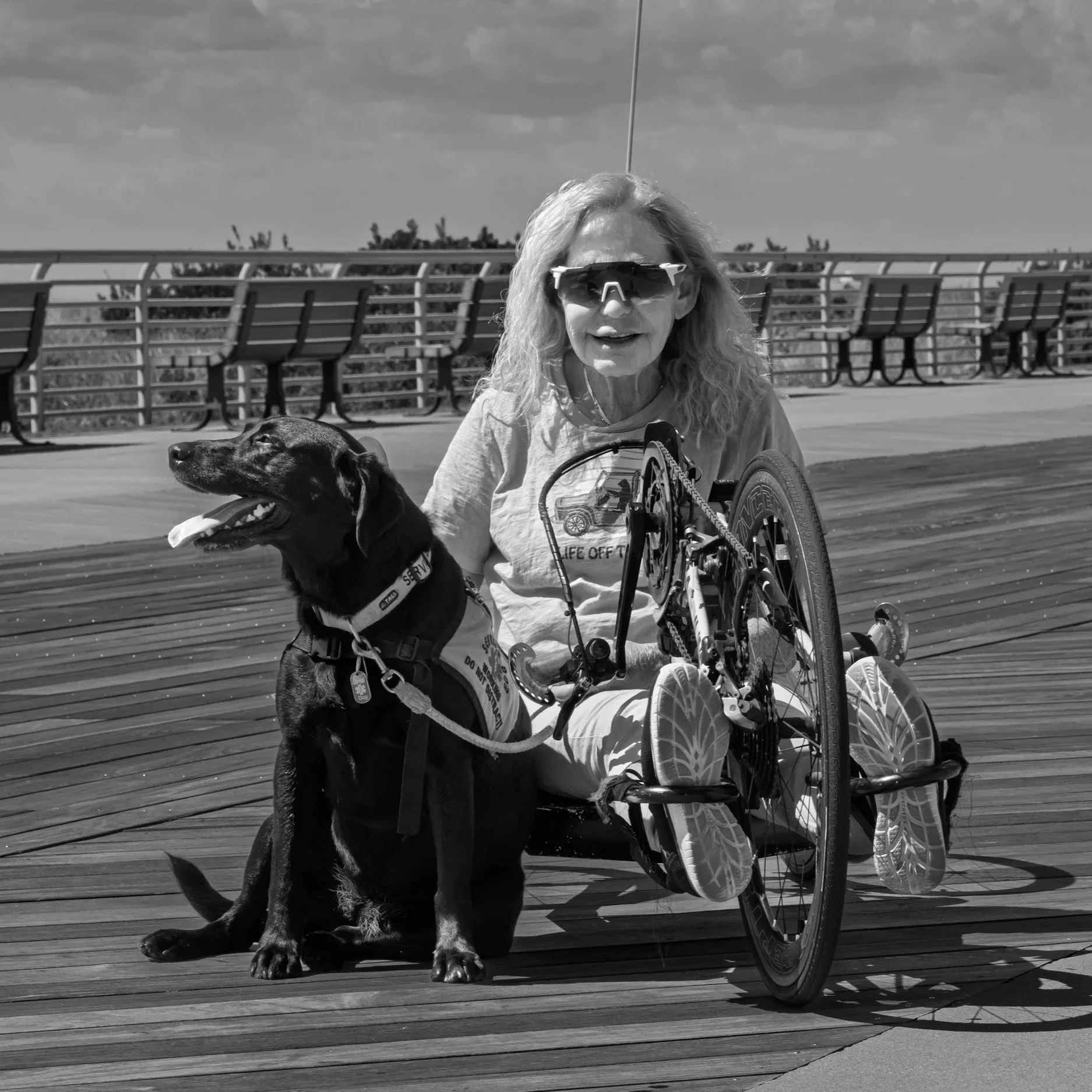 femme a velo alongé se promenant avec son chien noir en laisse