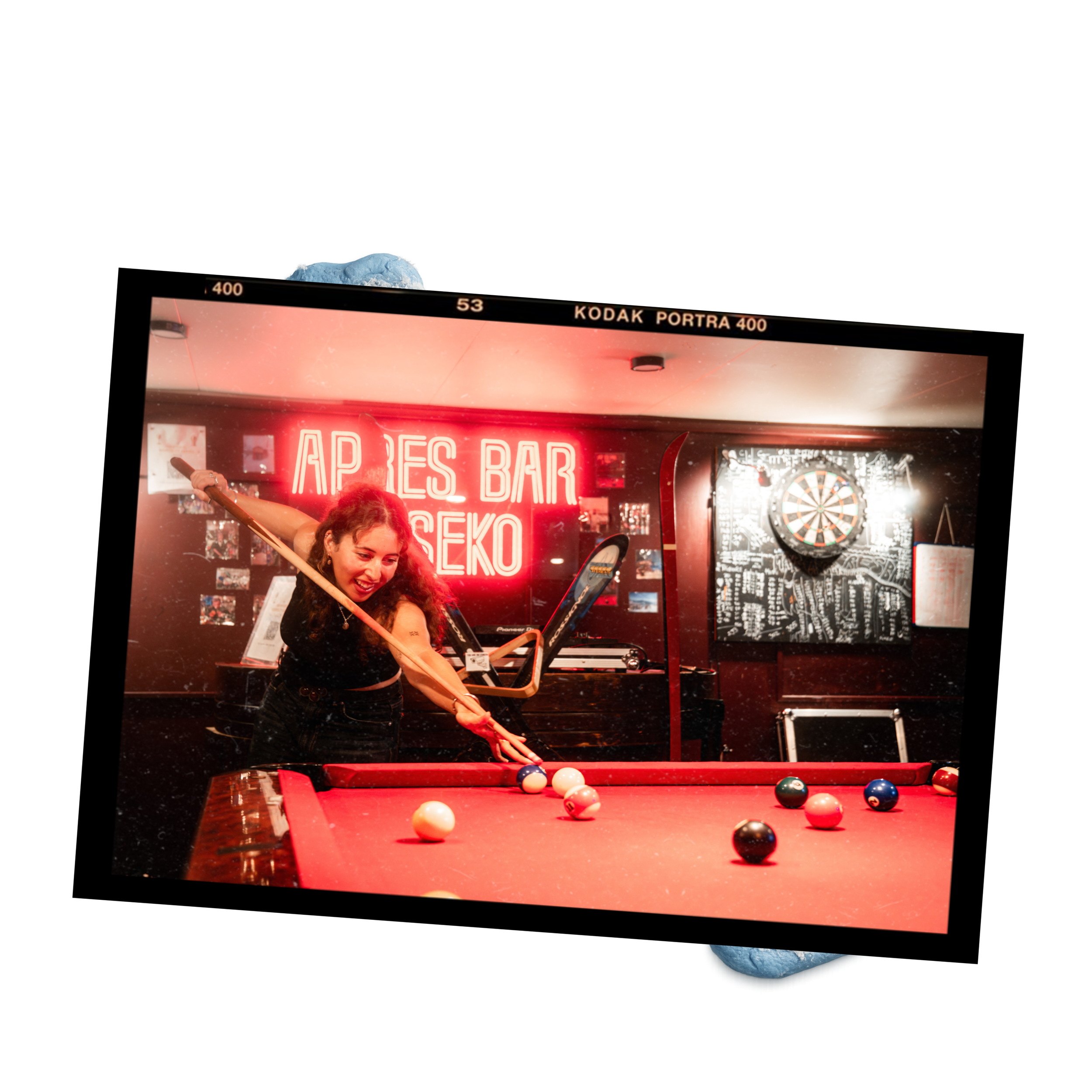 A woman playing pool at a bar with a red neon sign that reads 'APRES BAR' and a dartboard on the wall.