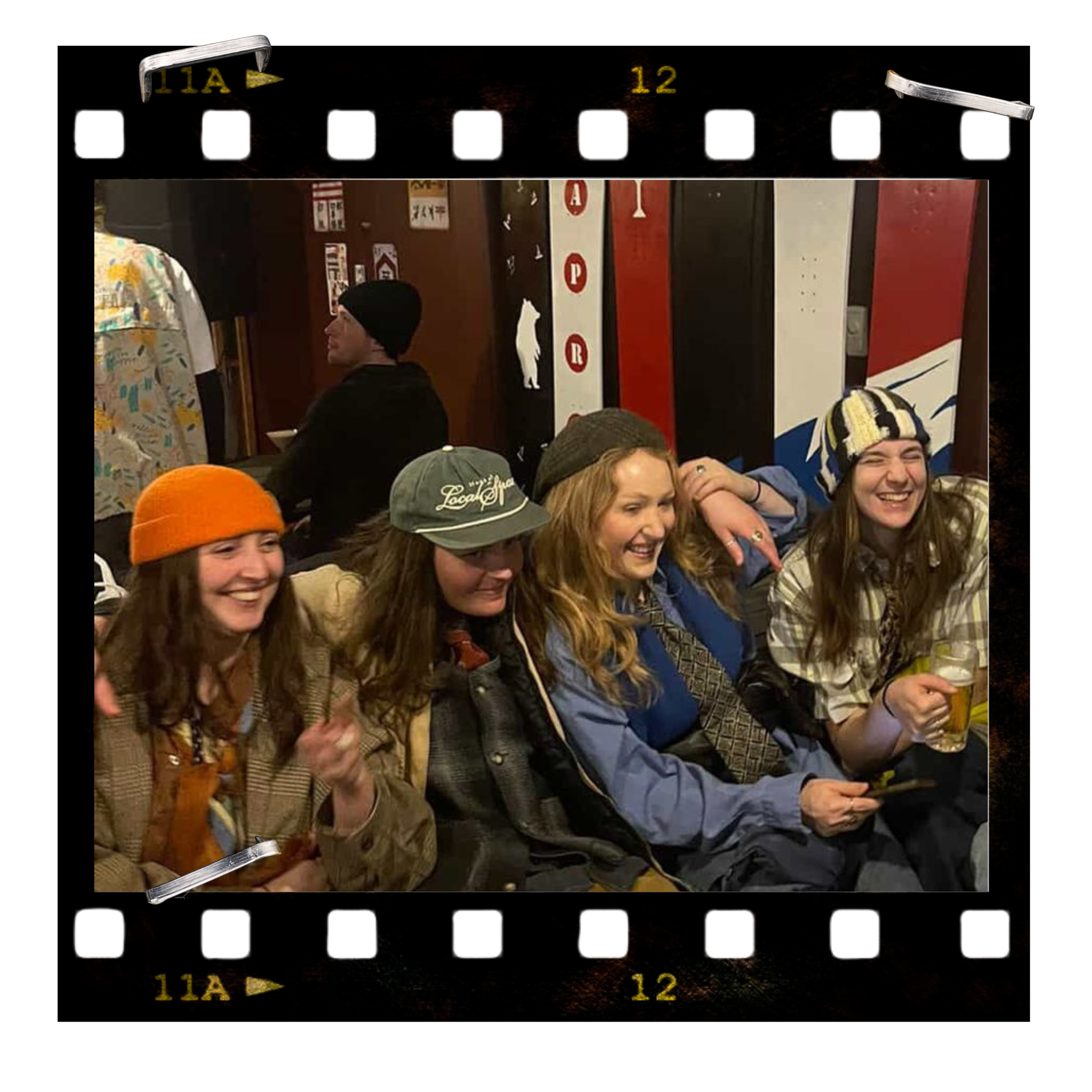 People enjoying a social gathering indoors with posters and decorations on the wall, some wearing hats and smiling.