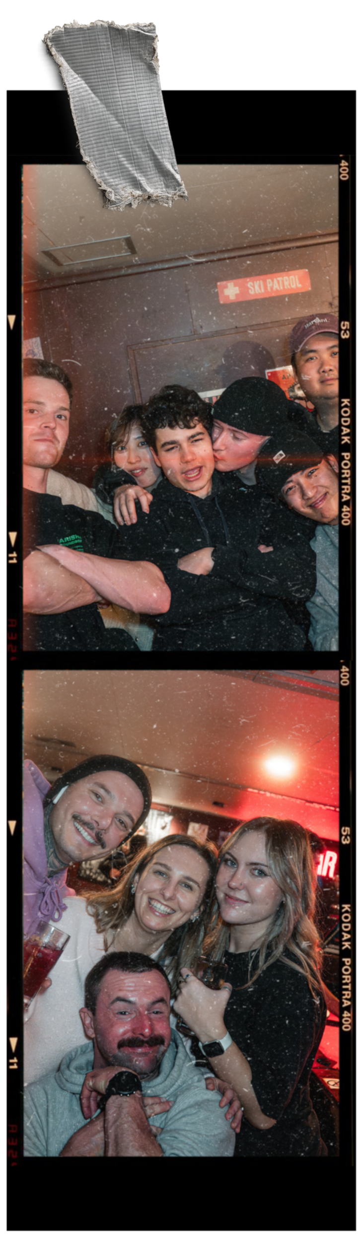 A group of five friends smiling and posing for a photo in a bar or restaurant. Some are holding drinks, and there is a sign that reads 'SKI PATROL' on the wall behind them. The setting has warm lighting and a casual atmosphere.