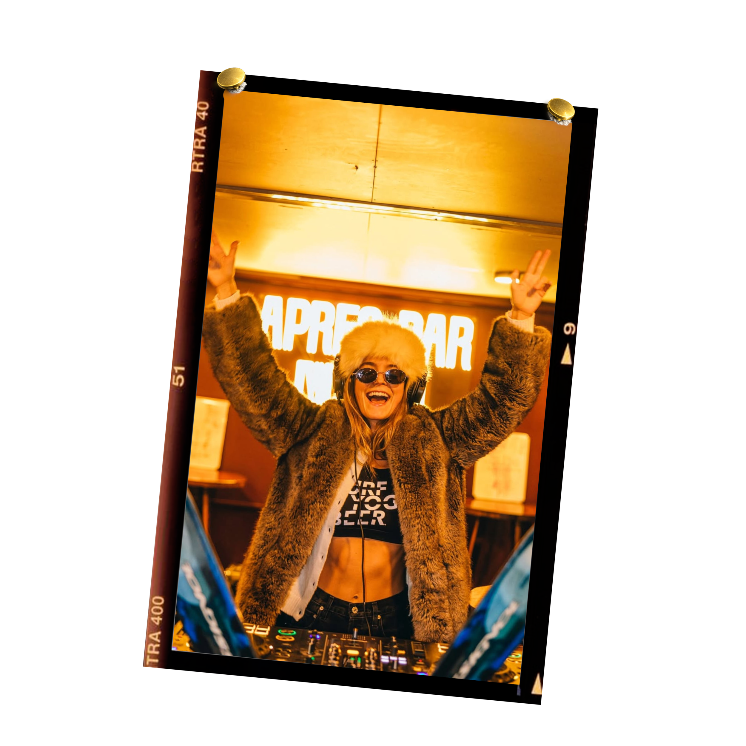 A woman wearing sunglasses and a furry coat smiling and raising her hands in front of a warm orange backlit sign that says "APPRECIATION."