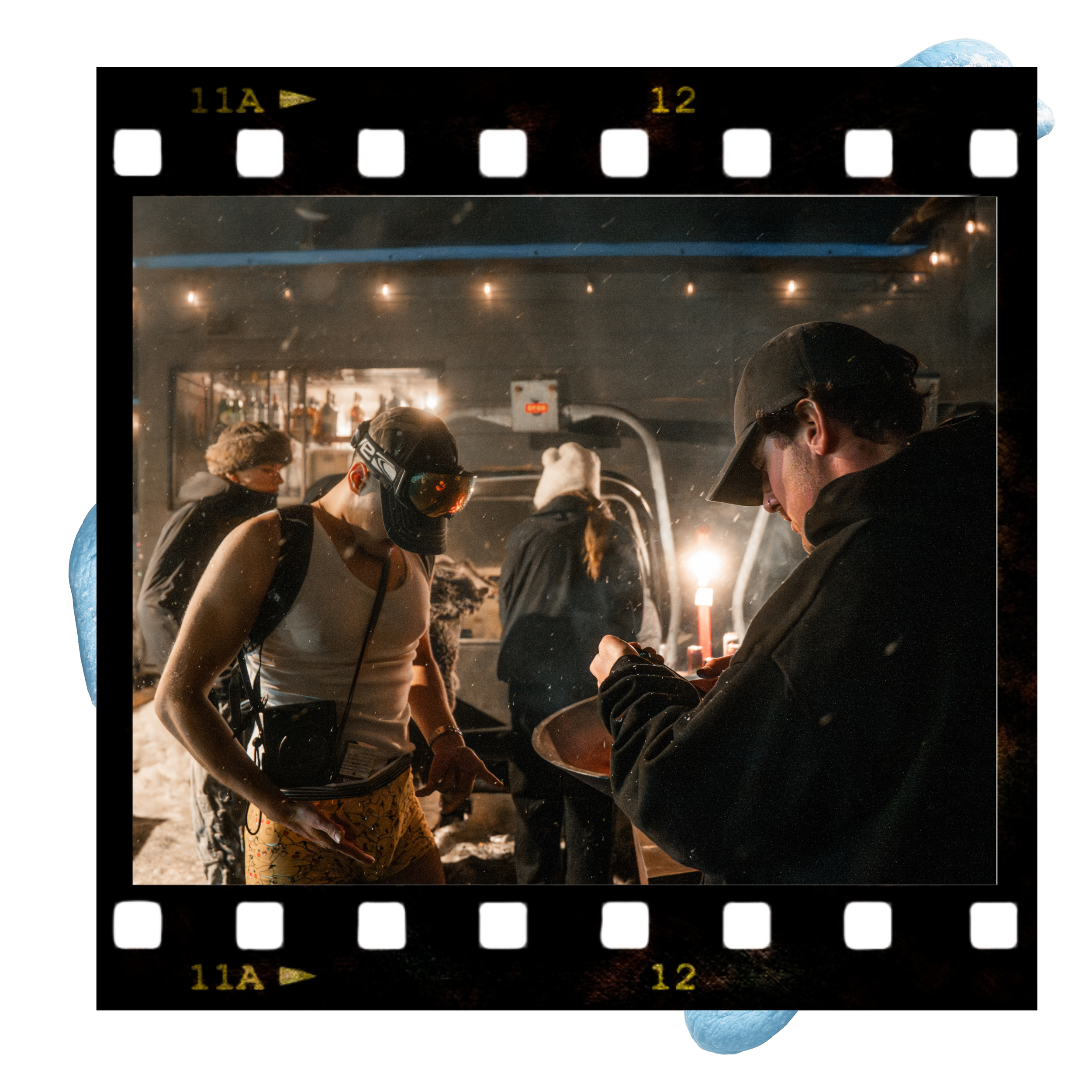 People gathering at a bar, possibly under a bridge or in an industrial setting, with a visible Earth in the upper right corner and a filmstrip border around the image.