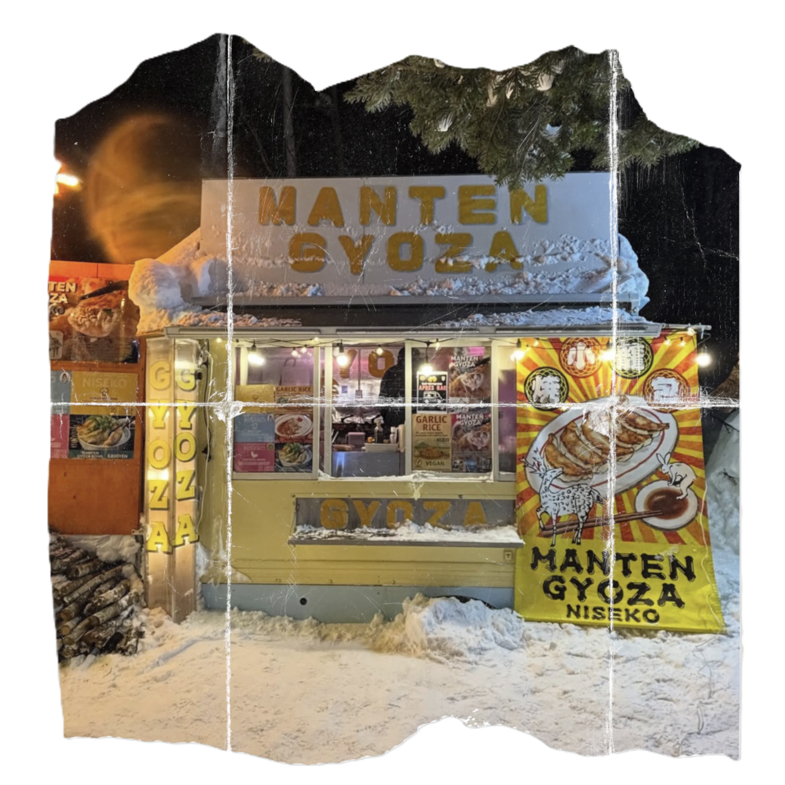 Ice sculpture of a sign with the words 'MANTEN GYOZA' carved in it, set outdoors with snow on the ground and trees in the background, illuminated by nearby lights.