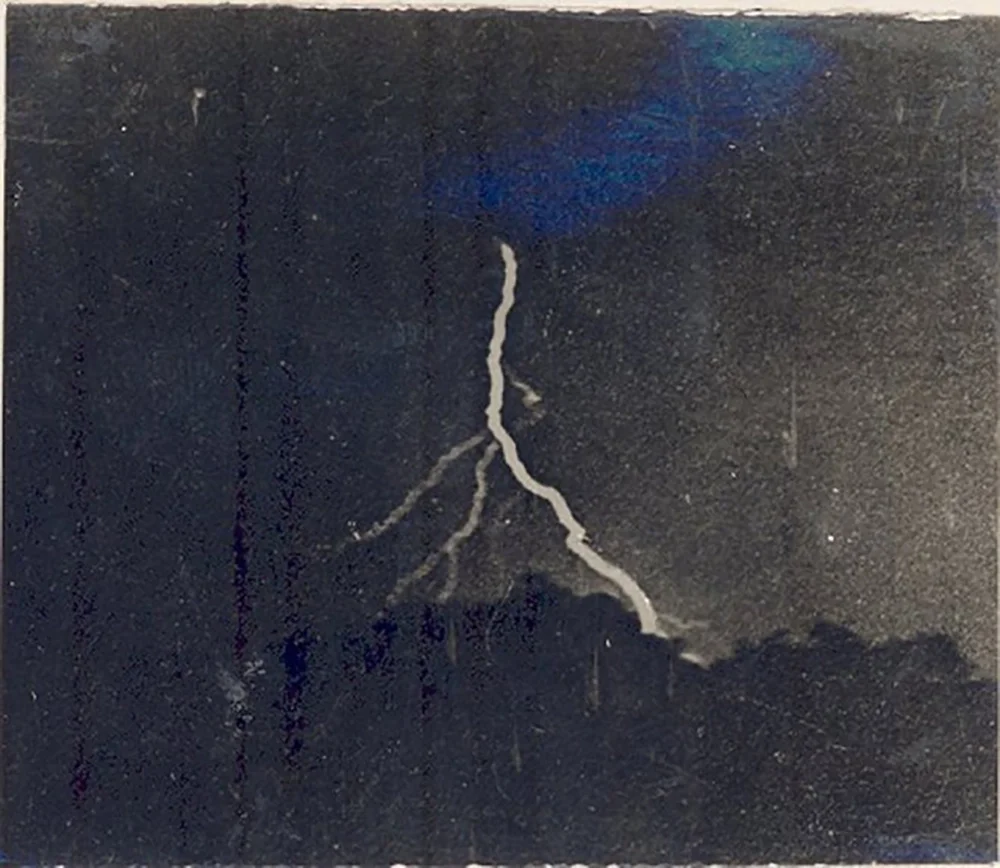 Jennings 1882: forked lightning across a dark sky — first photograph of lightning, the surface carrying both the strike and the years since.