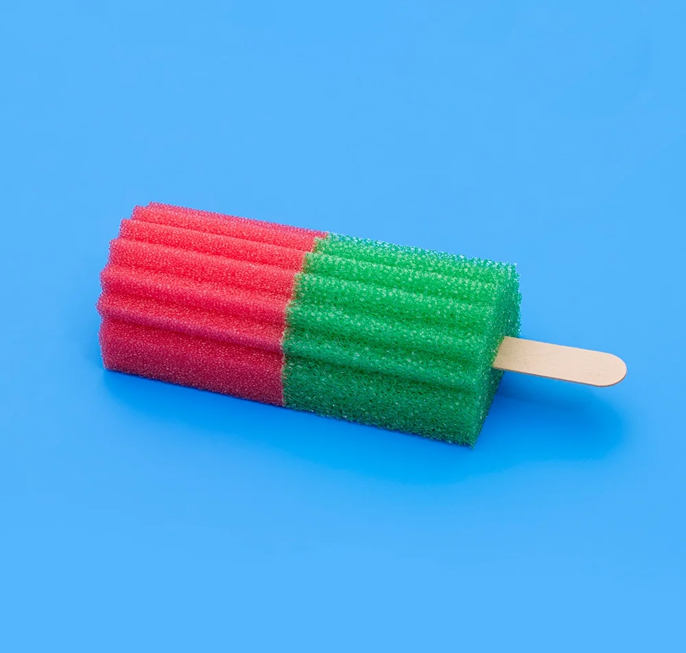 PUTPUT, Popsicle: a red-and-green popsicle on a wooden stick, sculpted from household sponges against bright blue — the key visual for Photo Basel 2026.