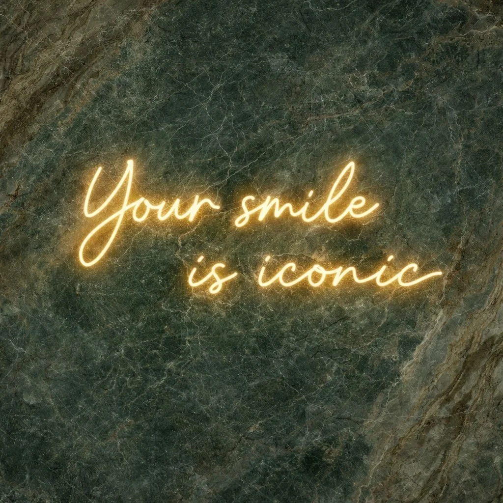 Neon sign on marble wall that says "Your smile is iconic" in cursive writing.