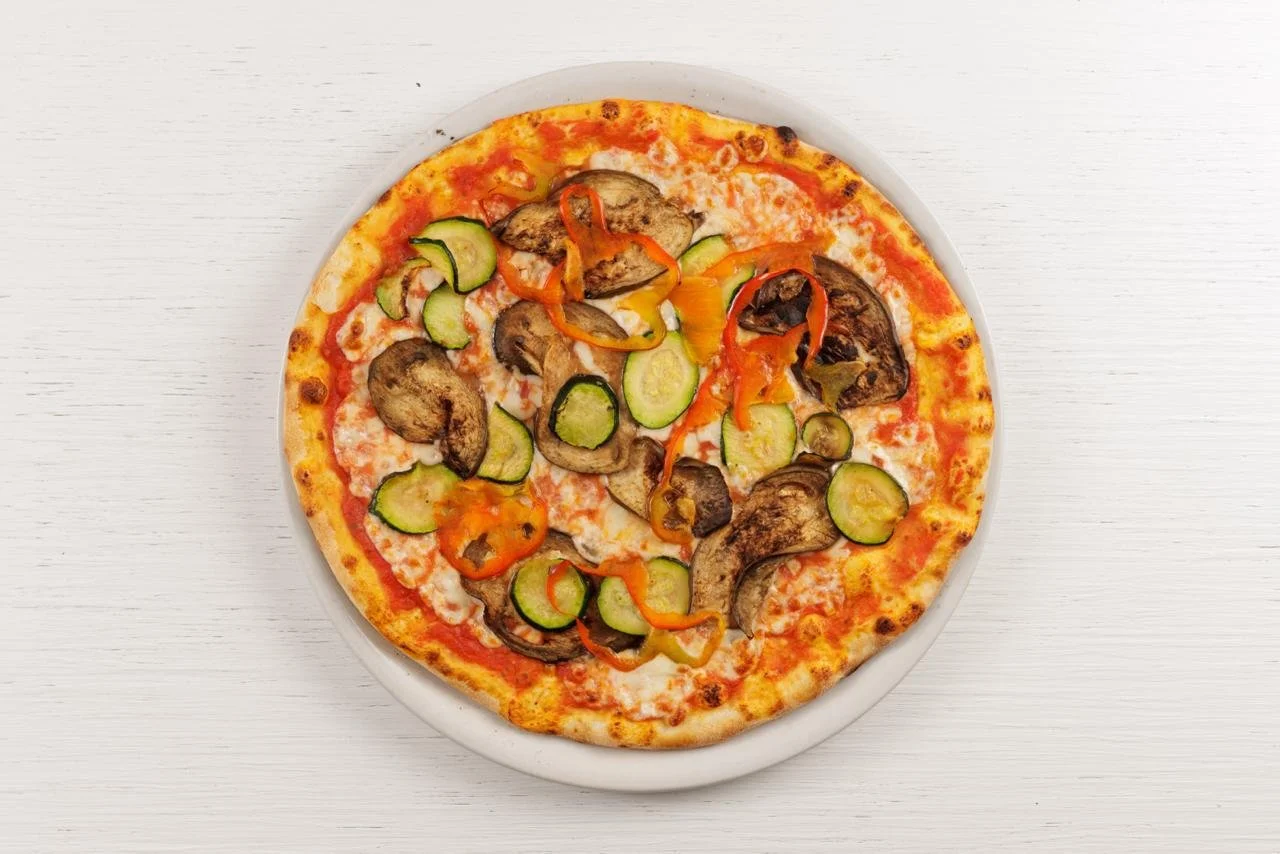 Pizza con funghi, zucchini e peperoni su una teglia bianca