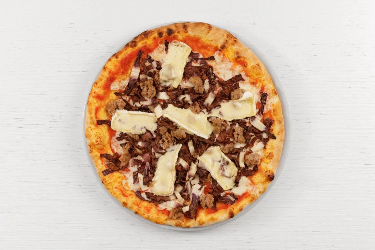 Pizza con formaggio, carne e prosciutto su una superficie bianca