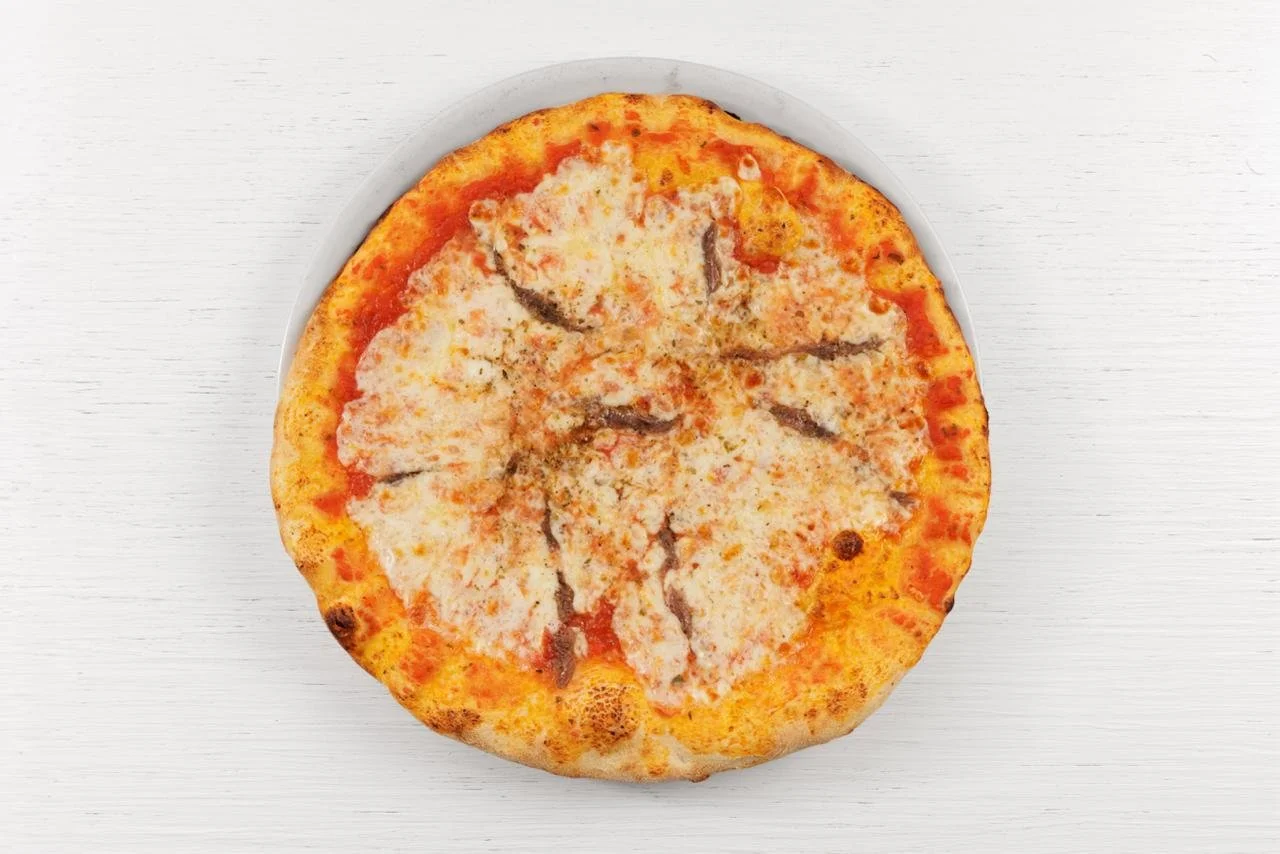 Una pizza margherita con formaggio, pomodoro e fettine di funghi, vista dall'alto su un piatto bianco.