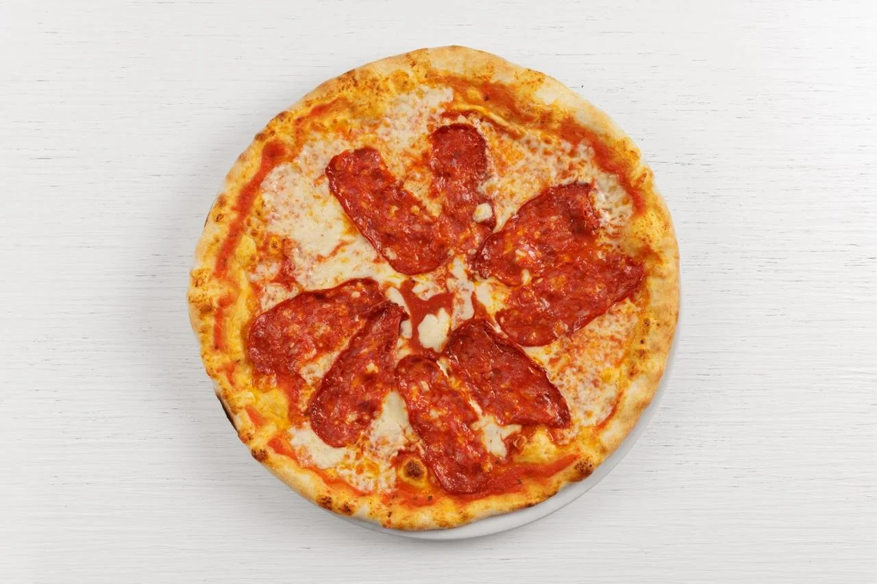 pizza con prosciutto e formaggio su un piatto bianco