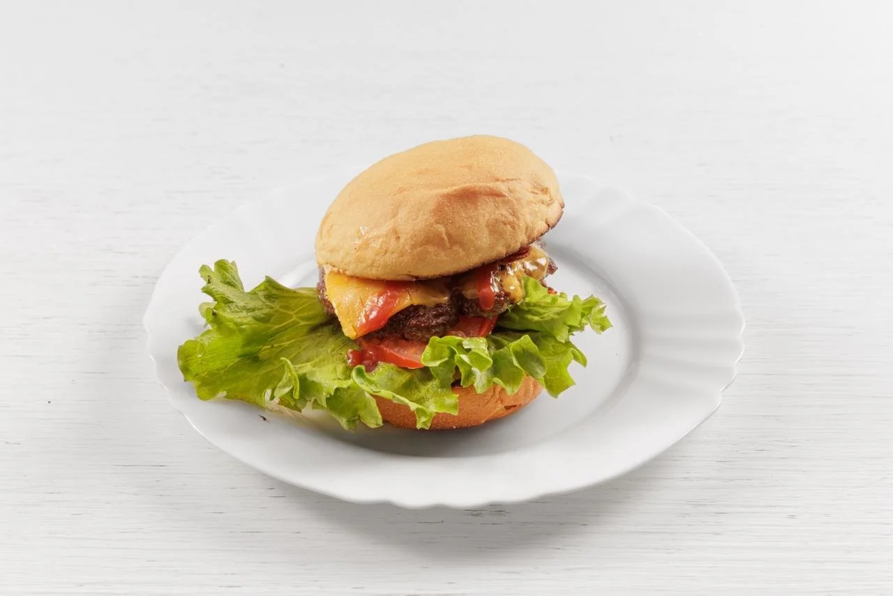 Panino con carne, formaggio, insalata e pomodoro su piatto bianco