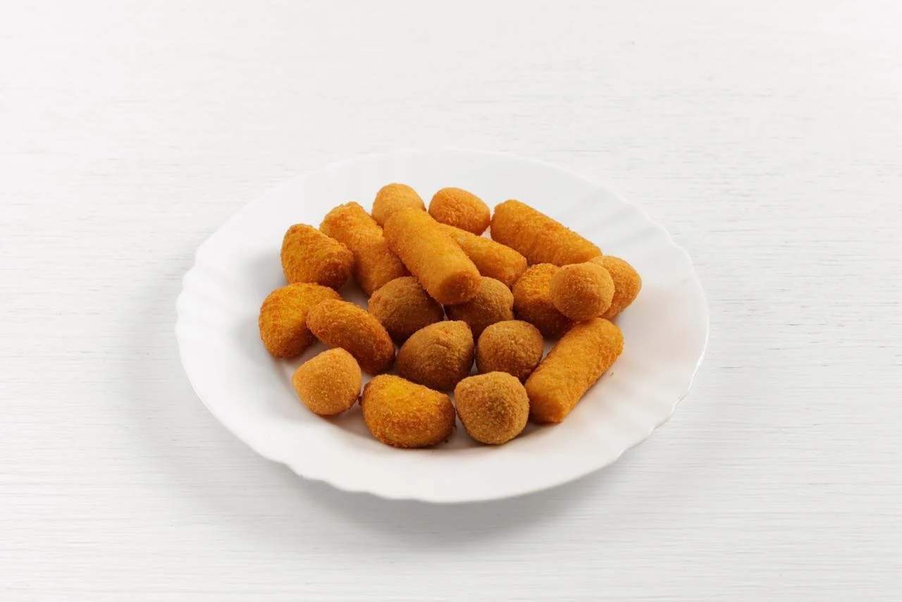 Assortimento di crocchette di pollo su un piatto bianco.