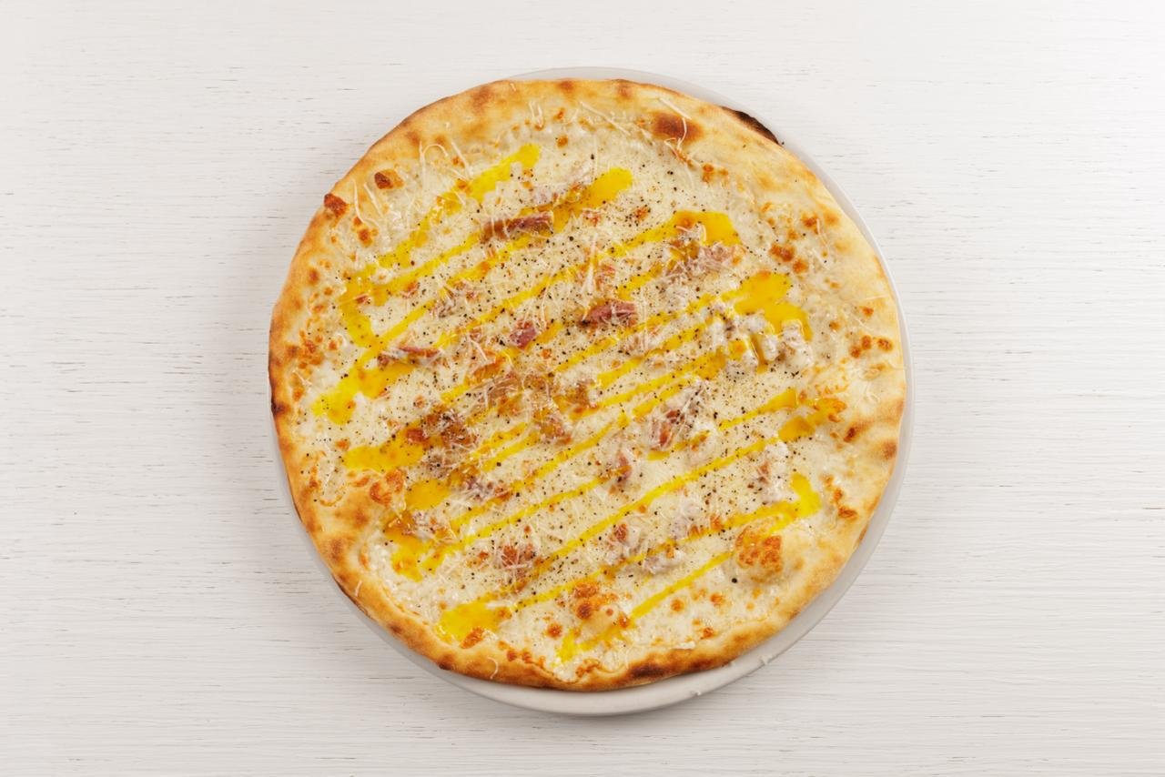 Pizza bianca con formaggio, prosciutto e olio d'oliva, disegni di olio e pepe sopra