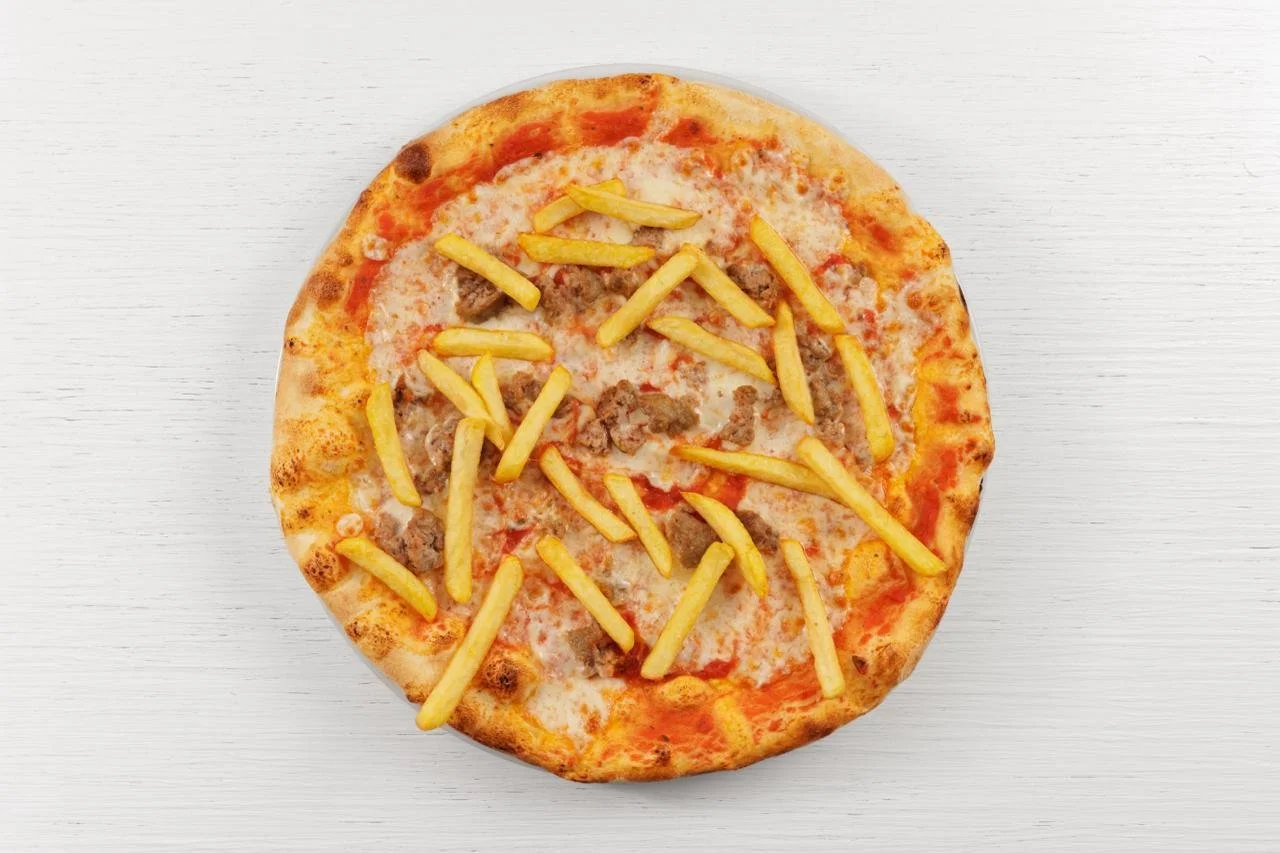 Pizza con patatine e carne su superficie chiara