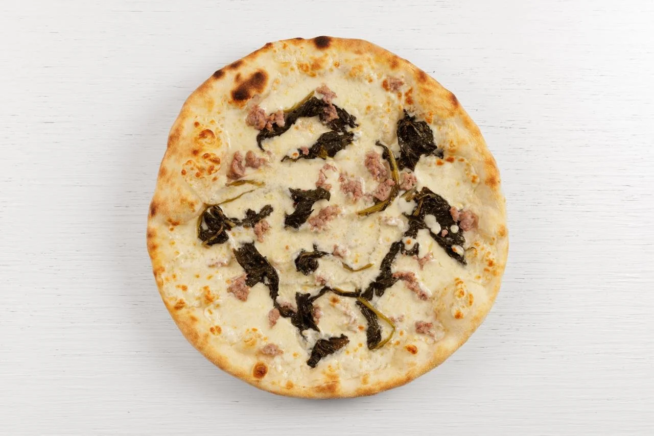 Pizza con formaggio, foglie di basilico e prosciutto cotto